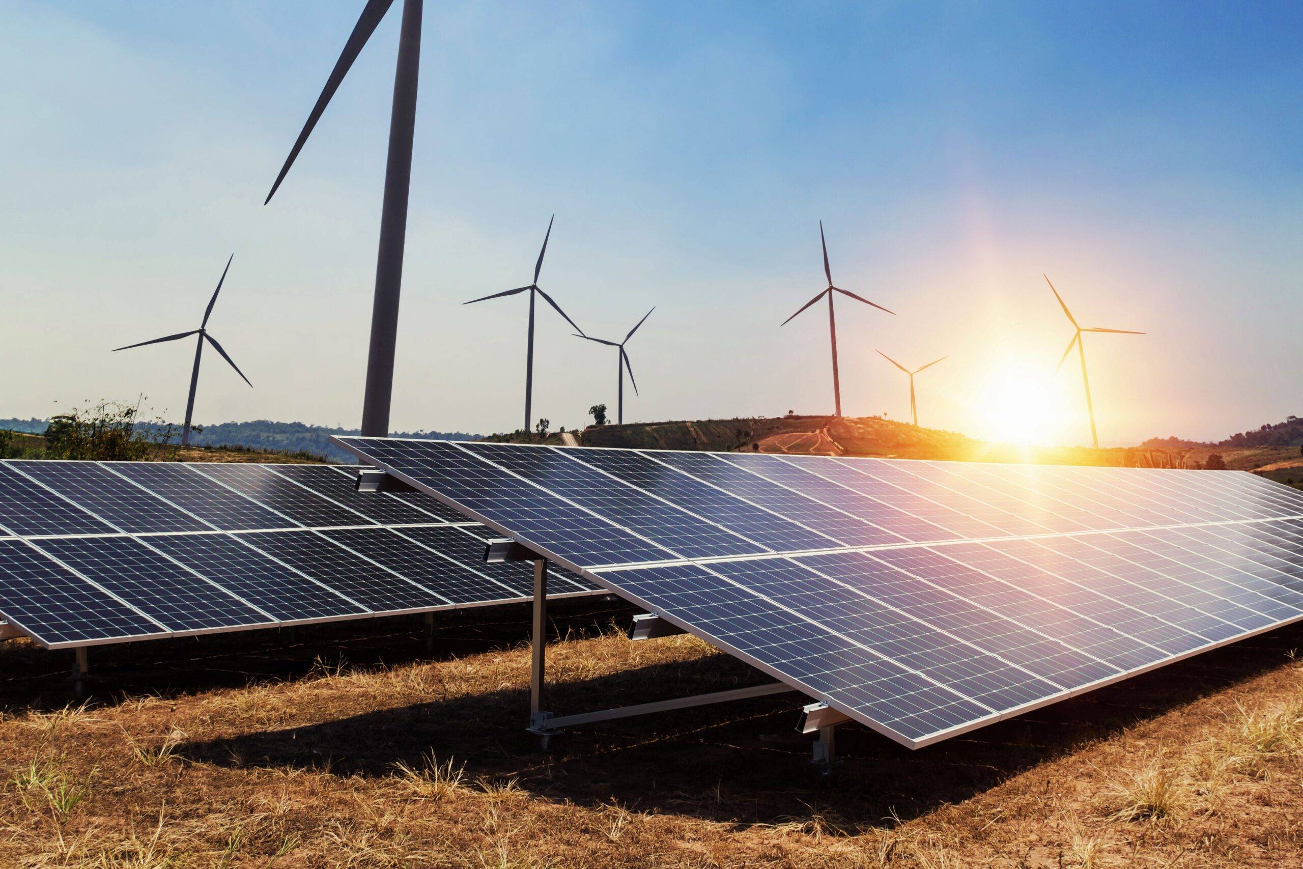 Solaranlagen sind im Vordergrund und im Hintergrund sind Windkraftwärke