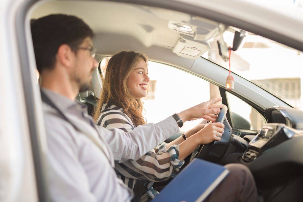 Junge Frau beim Fahrtraining in Zürich, unterstützt von einem Fahrlehrer während der Fahrstunde.